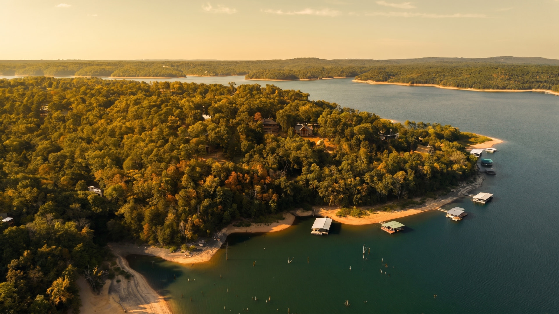 Aerial landscape of a winding lake surrounded by autumn-tinged hills and scattered docks