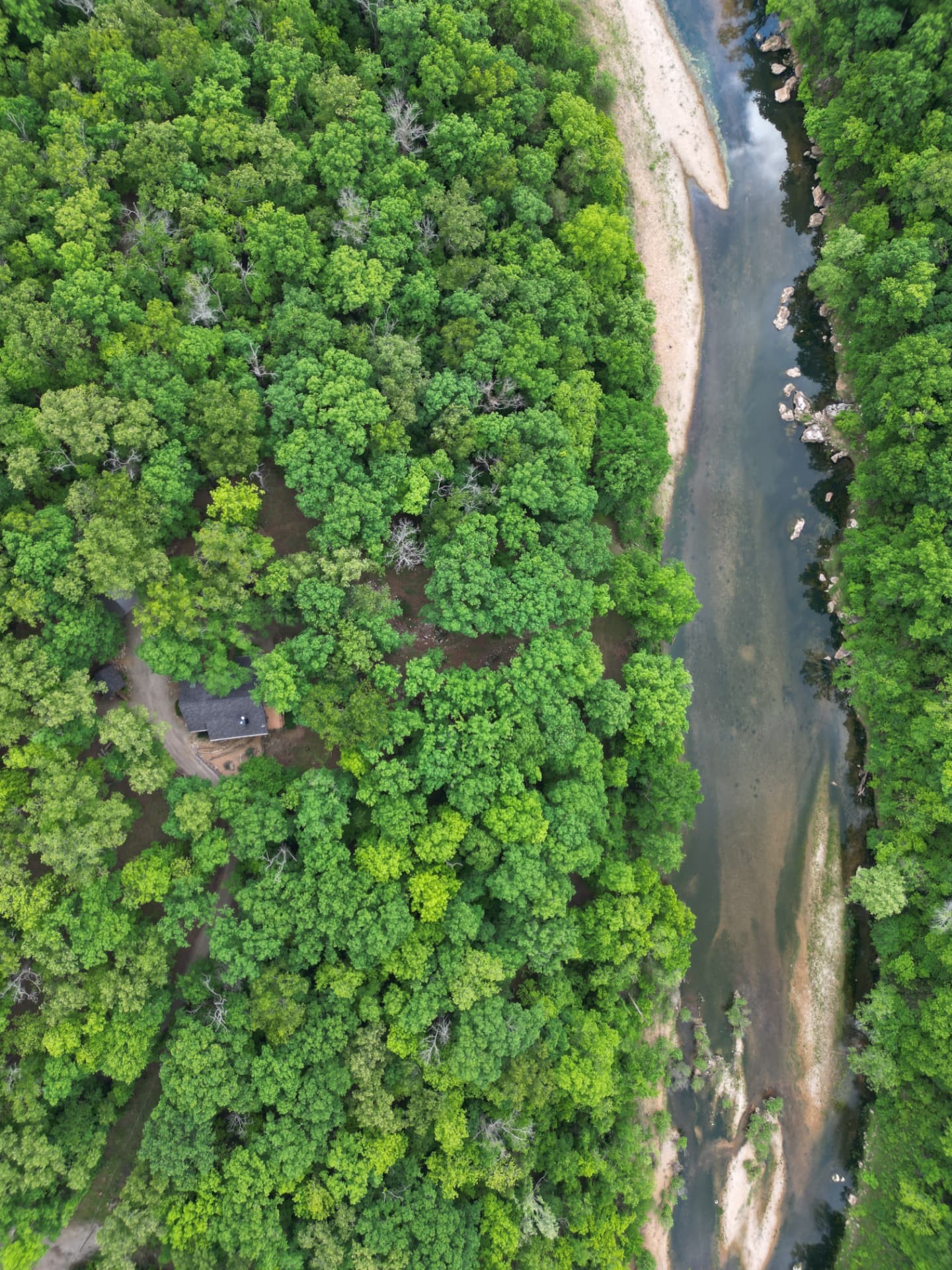 Top-down drone view of a remote cabin beside an Ozark river